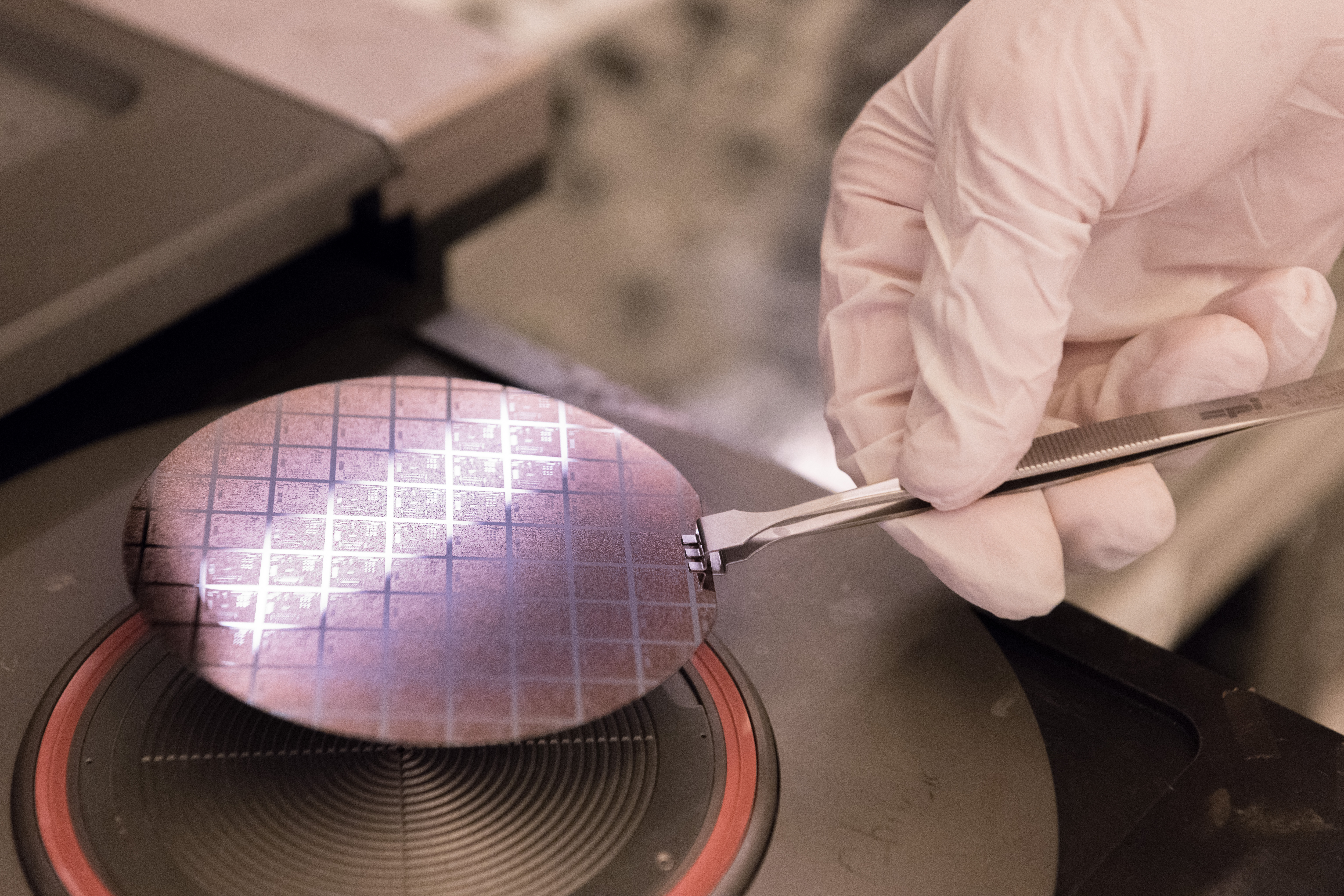 Gloved hand holds a wafer for microelectronics packaging 