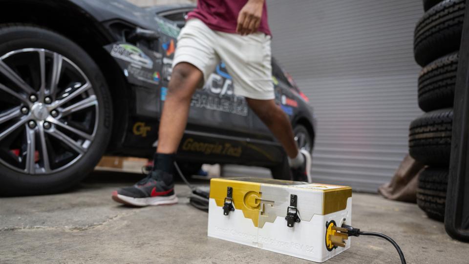 A gold and white charger box in front of a car