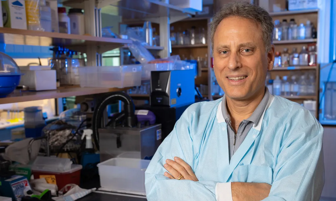 Mark Prausnitz poses with arms crossed in his lab with shelves of materials and bottles in the background.